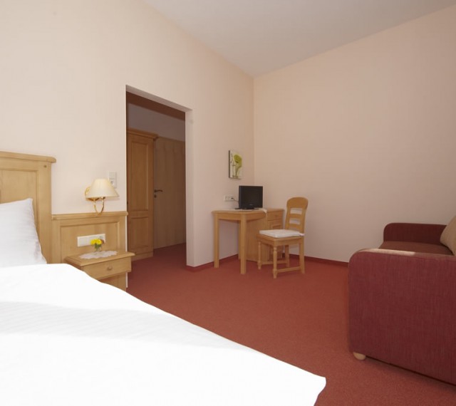 Schlafzimmer mit gemütlicher Sitzecke und TV